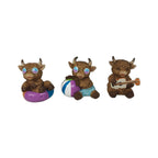 Three small brown cow figurines posed together on a plain white background. One cow sits in a purple float, one wears blue swim trunks and holds a striped beach ball, and one plays a guitar.