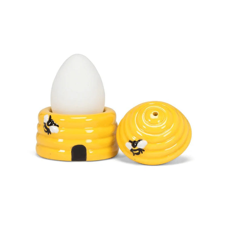 Yellow bee hive-shaped egg holder with a white egg on a white background