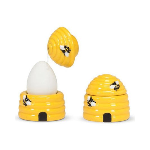 Yellow bee hive-shaped egg holders with a white egg on a white background