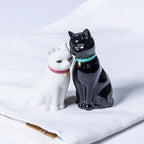 Black and white cat-shaped salt and pepper shakers on a white tablecloth.