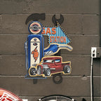 Decorative sign with gas station and truck design on a textured wall.