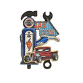 Decorative sign with gas station and truck design on a textured wall.