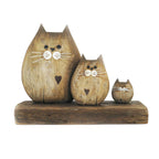 Three rustic wooden cat figurines in different sizes sitting on a matching wooden base against a plain white background.